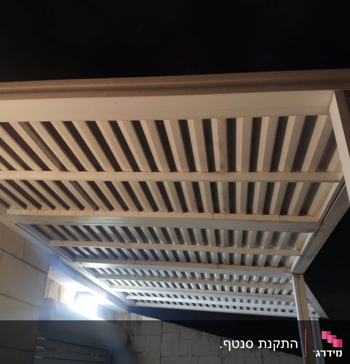 פרגולה מתכתית עם קורות אופקיות בלילה